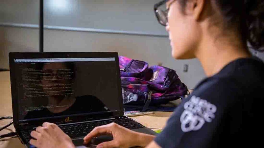 A woman focused on her work while typing on a laptop computer at a desk.